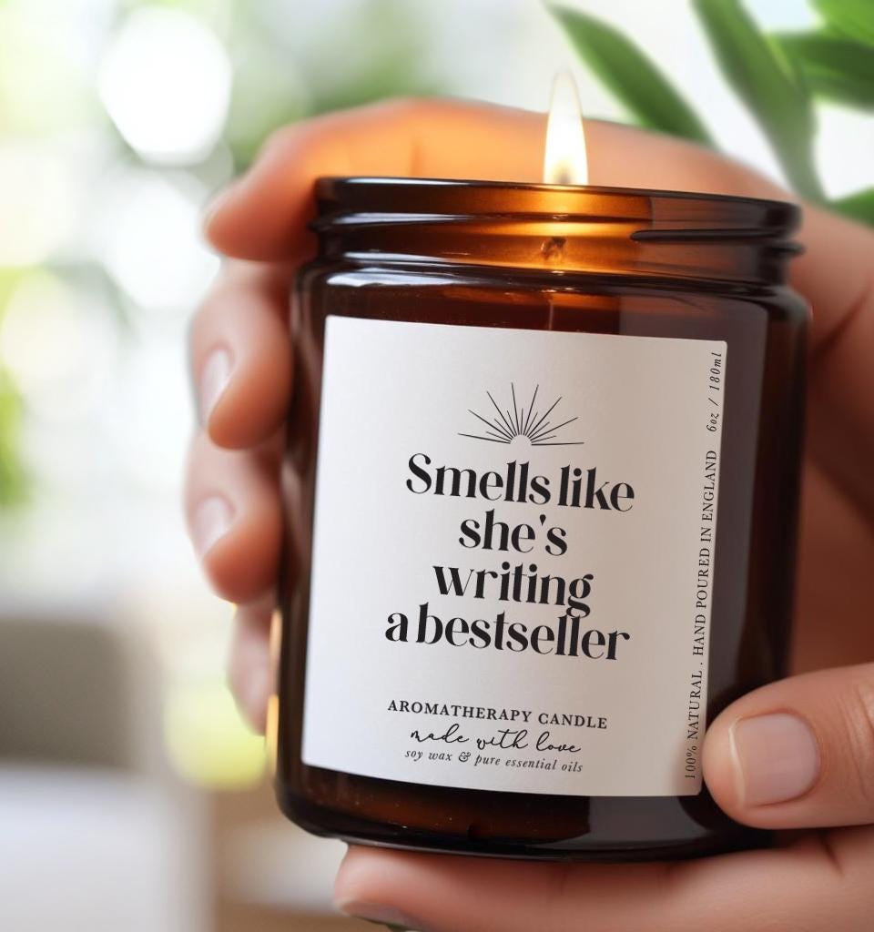 Candle with label that reads 'Smells like she's writing a best seller', 100% Natural Soy Wax Essential Oil aromatherapy candle gift